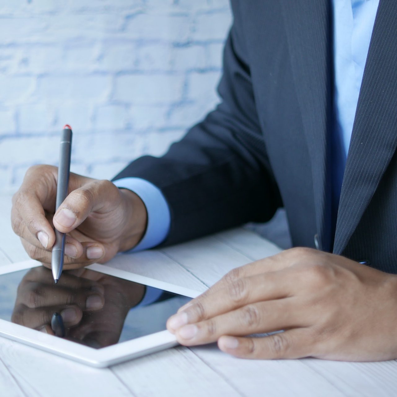 a man in a suit writing on a tablet